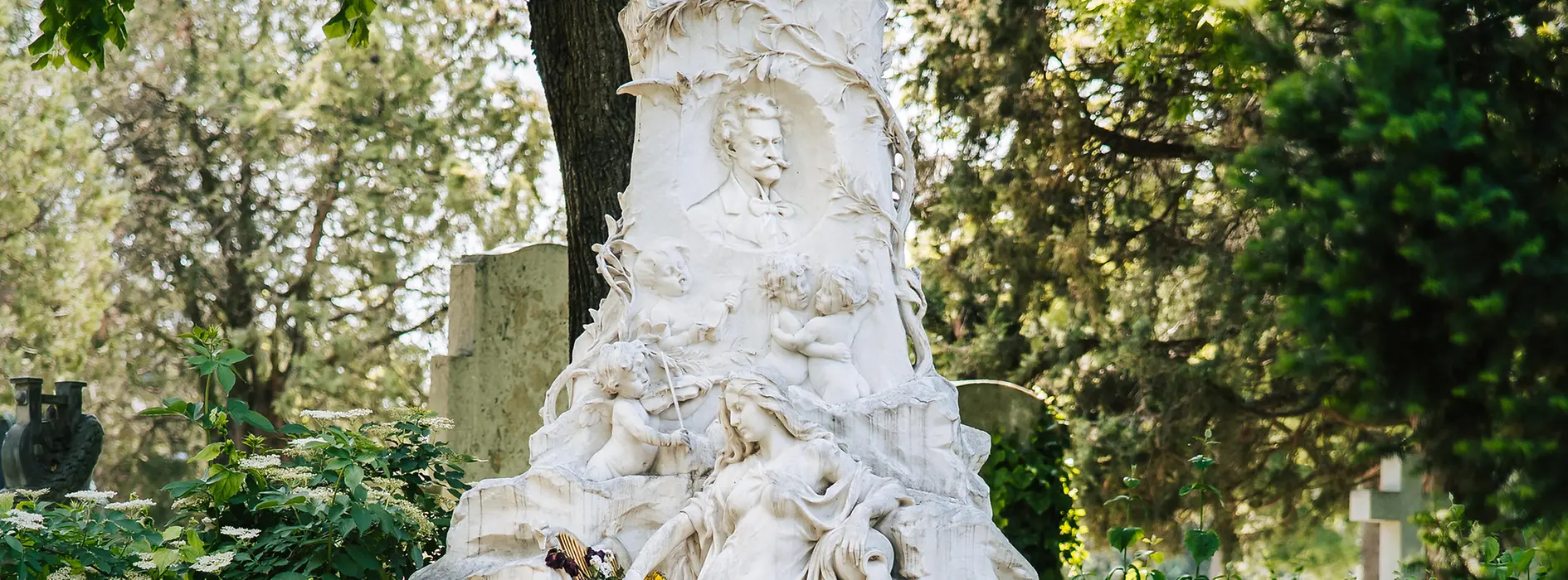 Marble tomb of Johann Strauss Sohn with his head in relief, plus a female figure, bat and an angel playing the violin in the towering monument.