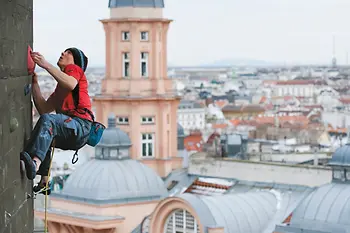Mann klettert am Flakturm vor Wien-Panorama