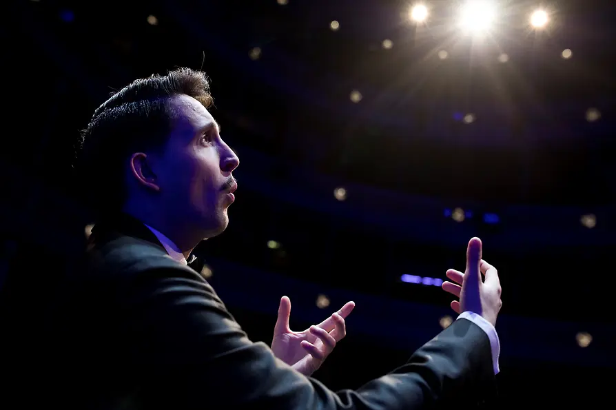 Nikolaus Habjan is an art whistler. Here he whistles on stage in a black suit.