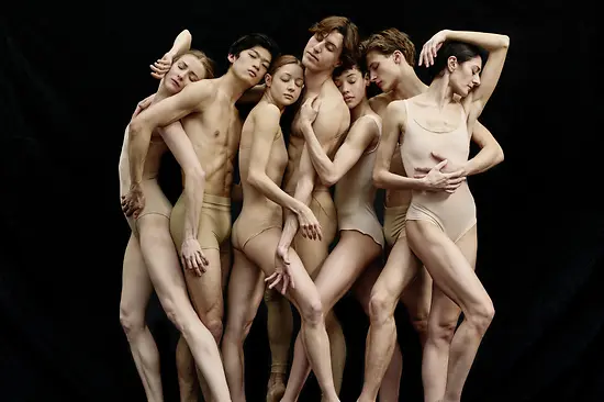 Seven ballet dancers standing close together in pose.