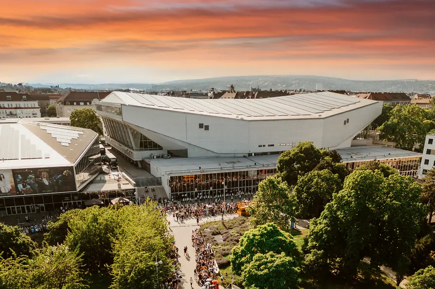 Aerial view of the Wiener Stadthalle at dusk, with people waiting to enter.
